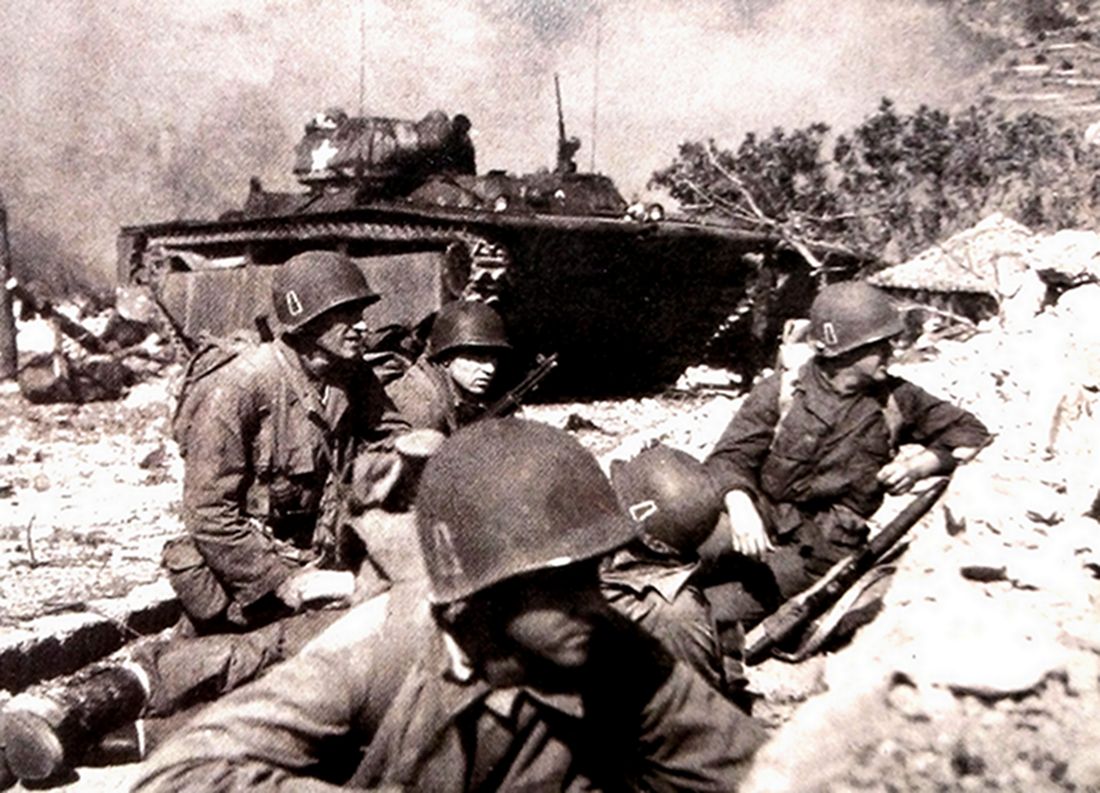 1945年4月，「冲绳岛战役」期间，在安装有75毫米短筒火炮的LVT4两栖装甲车火力支援下，刚登上海岛的美军士兵正在沙石掩护下作进攻准备。