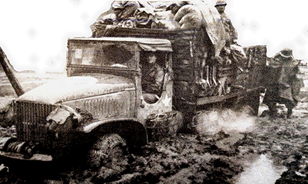 1944年西线运输线,美军一辆向前线运送物资的GMC CCKW 353B型卡车陷入泥泞困境中,要靠士兵下车推车助力。