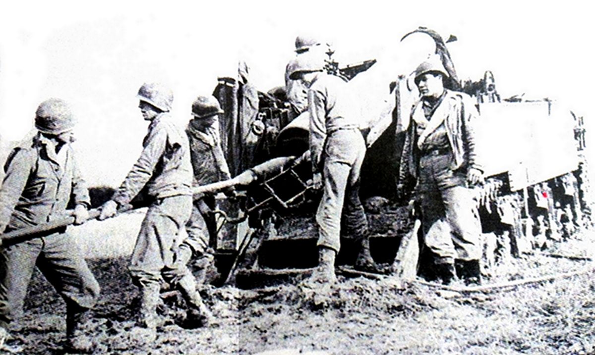 1944年9月，「洛林战役」期间，美军一辆M12自行火炮的炮兵正将155毫米炮弹的弹丸压入炮膛，155毫米炮弹分为两部分，炮弹推进剂另用袋装分离。