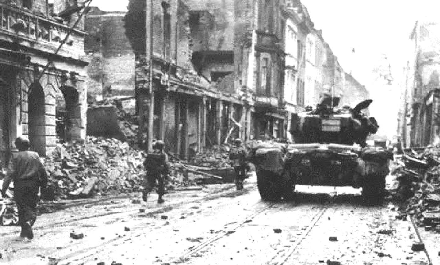 1945年春,在德国,美军一辆M26「潘兴」重型坦克掩护步兵沿城市街道前进。