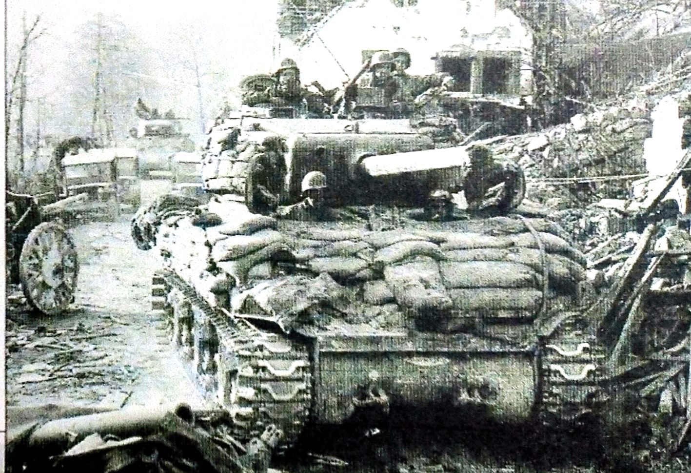 1945年3月23日,「莱茵河战役」期间,行进在德国Silz地区附近的美军第14装甲师的一辆M4A1(76)中型坦克。此地区刚经历了一场激烈战斗,坦克周围都是废墟和德军败退时遗弃的装备,这辆坦克也使用了沙袋作为加强防护。
