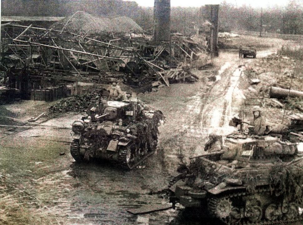 1945年3月7日,在德国Bad Godesberg镇郊区外围,两辆隶属美军746坦克营的M5A1轻型坦克经过一个被摧毁的工厂。它们正在支援美军第9步兵师的战斗,该师当天正试图夺取这个城镇,配合美军第9装甲师沿着莱茵河进攻。