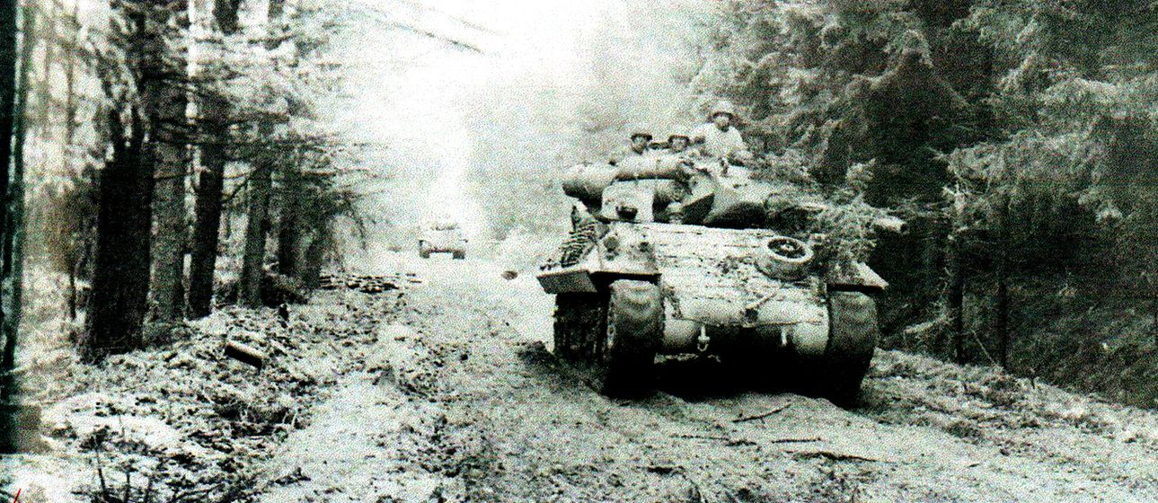 1944年11月4日,「赫特根森林战役」期间,美军第893坦克歼击营的M10坦克歼击车正沿着通向施密特的林间道路前进,试图增援被德军第116装甲师豹式坦克攻击的美军步兵部队,其中3辆M4坦克最先抵达并迟缓了德军攻势。这一场在赫特根森林里主要由美军步兵部队进行的战斗,也成为1944至1945年间美军在欧洲几场最为血腥的战斗之一。
