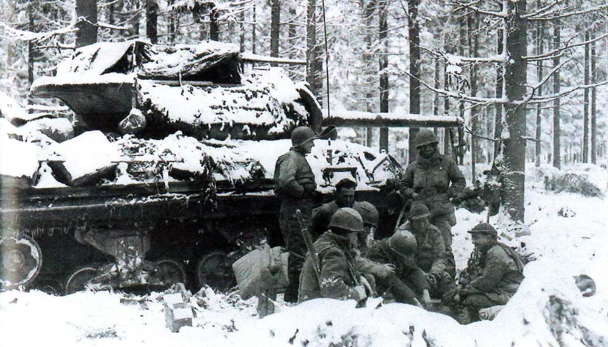 1945年1月20日,比利时Courtil附近地区,美军第629坦克歼击营一辆M10坦克歼击车的车组成员正和第331步兵团的士兵们围在火堆旁取暖。
