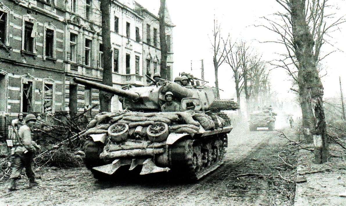 1945年2月24日,一辆正在支援美军第8步兵师作战行动的M10坦克歼击车经过法国Durne地区。战车安装了Culin树篱切割器,车体四周携带了沙袋和原木作附加防护以对抗德军反坦克火箭筒。