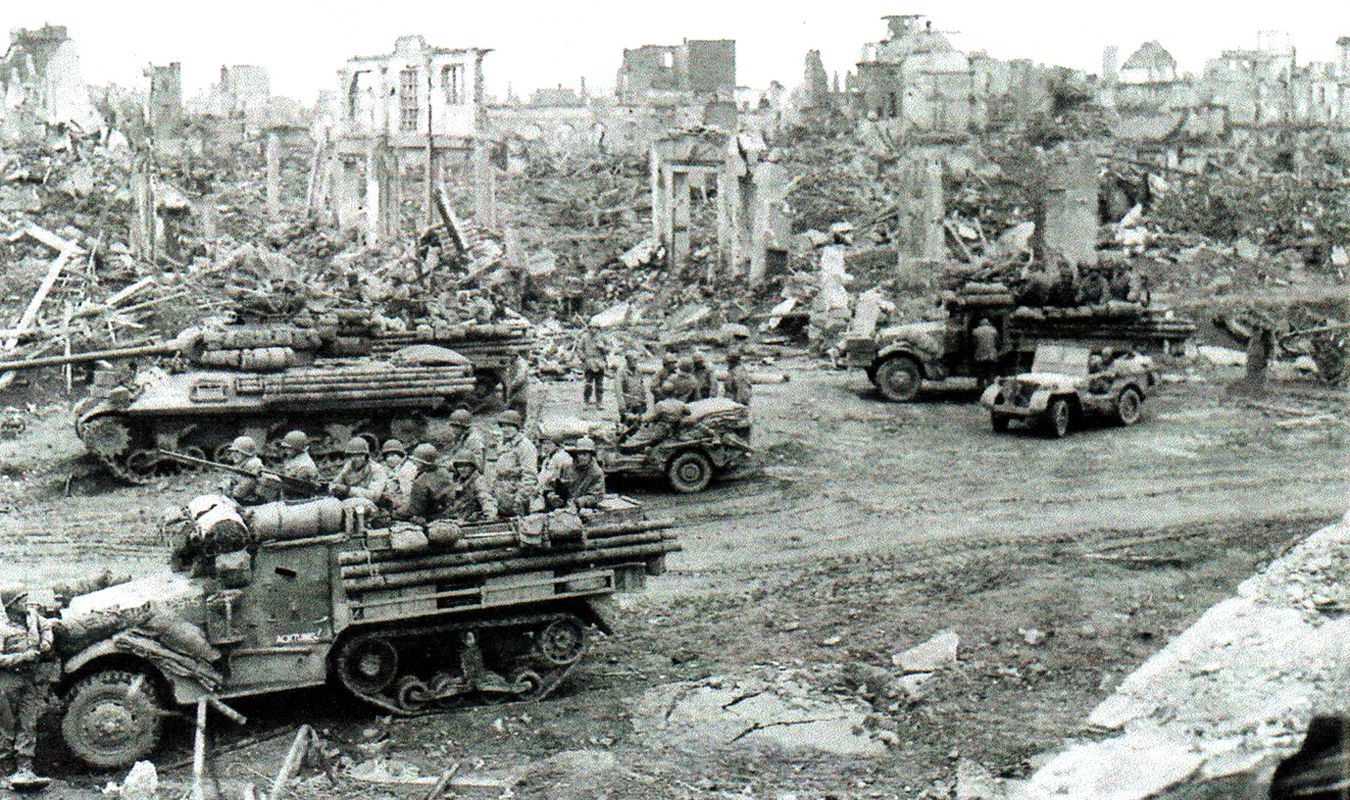 1945年2月26日,「莱茵兰战役」期间,一辆M36 90毫米火炮坦克歼击车在德国杜伦的废墟中护卫着一队第3装甲师23装甲工程团的半履带卡车。其车身上挂载的圆木条应是用于工程建筑的目的,而非作为其附加装甲。