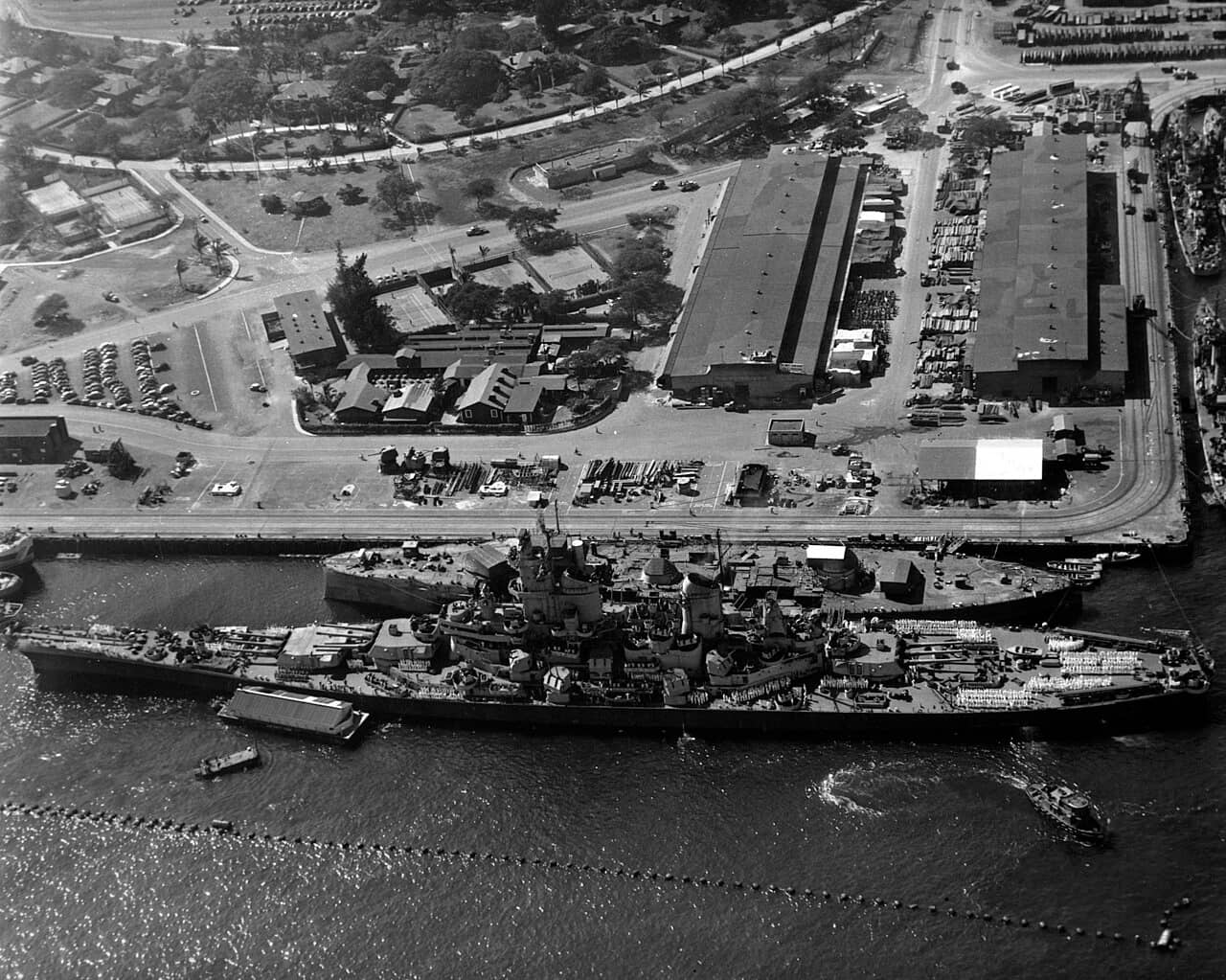 1944年11月11日,夏威夷珍珠港海军基地,美国海军衣阿华级战列舰「威斯康星」号(BB-64)停靠在「俄克拉何马」号战列舰(BB-37)的残骸外侧。请注意两艘战列舰在长度上的巨大差异,以及舰体外侧设置的防鱼雷网。