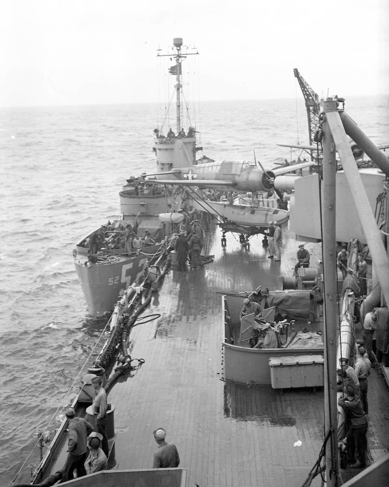 1945年2月22日,硫磺岛外海,步兵登陆艇 LCI-52 靠帮「内华达」号(BB-36)转运人员与物资,舰尾可见一架 OS2U「翠鸟」水上侦察机。