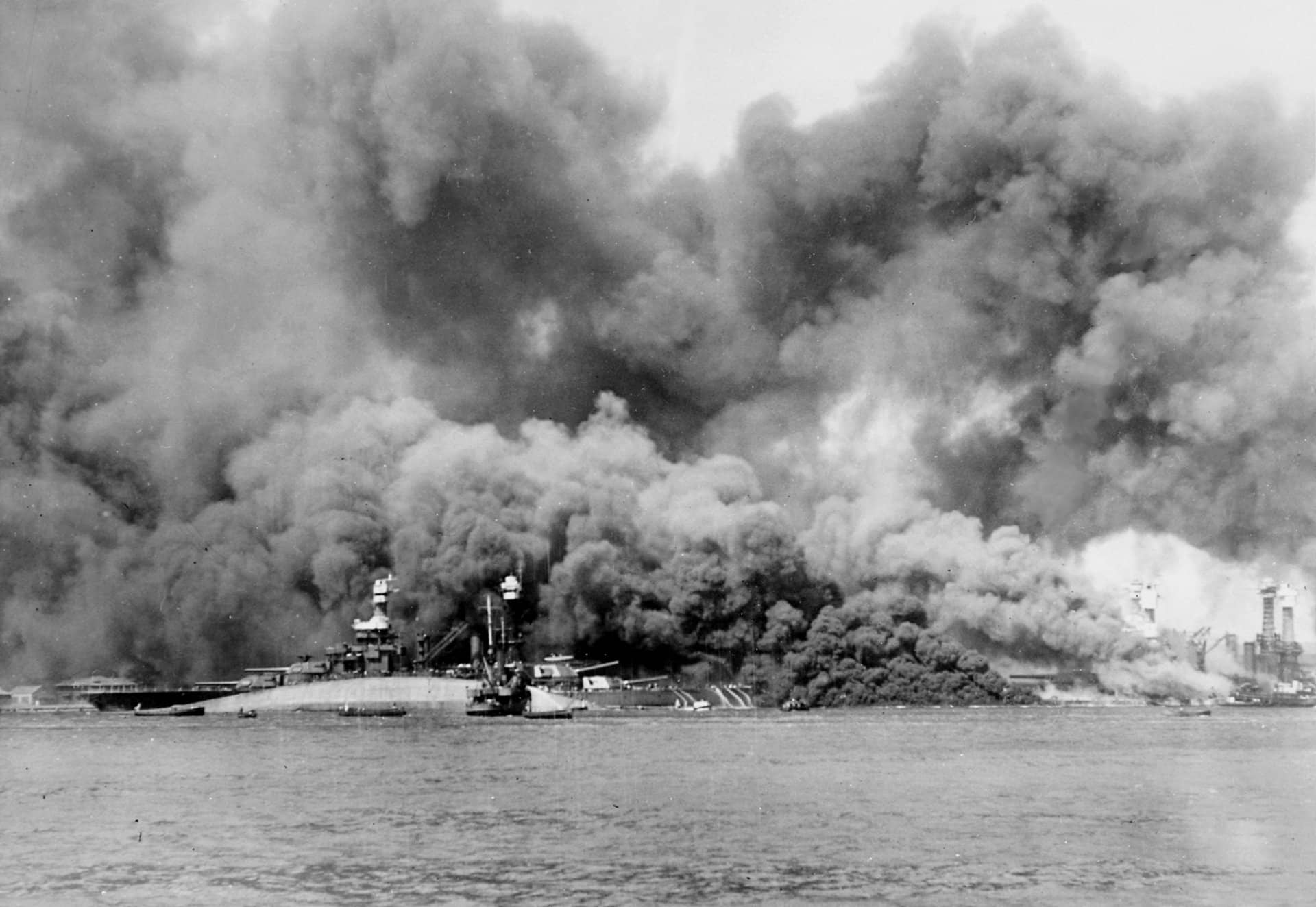 1941年12月7日,日军袭击珍珠港后的「战列舰停泊线」(Battleship Row)。前景中可见已倾覆的「俄克拉何马」号战列舰(BB-37);其后方是「马里兰」号战列舰(BB-46);右侧则是正在猛烈燃烧的「西弗吉尼亚」号战列舰(BB-48)。注:「珍珠港偷袭」共造成「俄克拉何马」号上429人阵亡,是美国海军二战中单舰伤亡最惨重的事件之一。