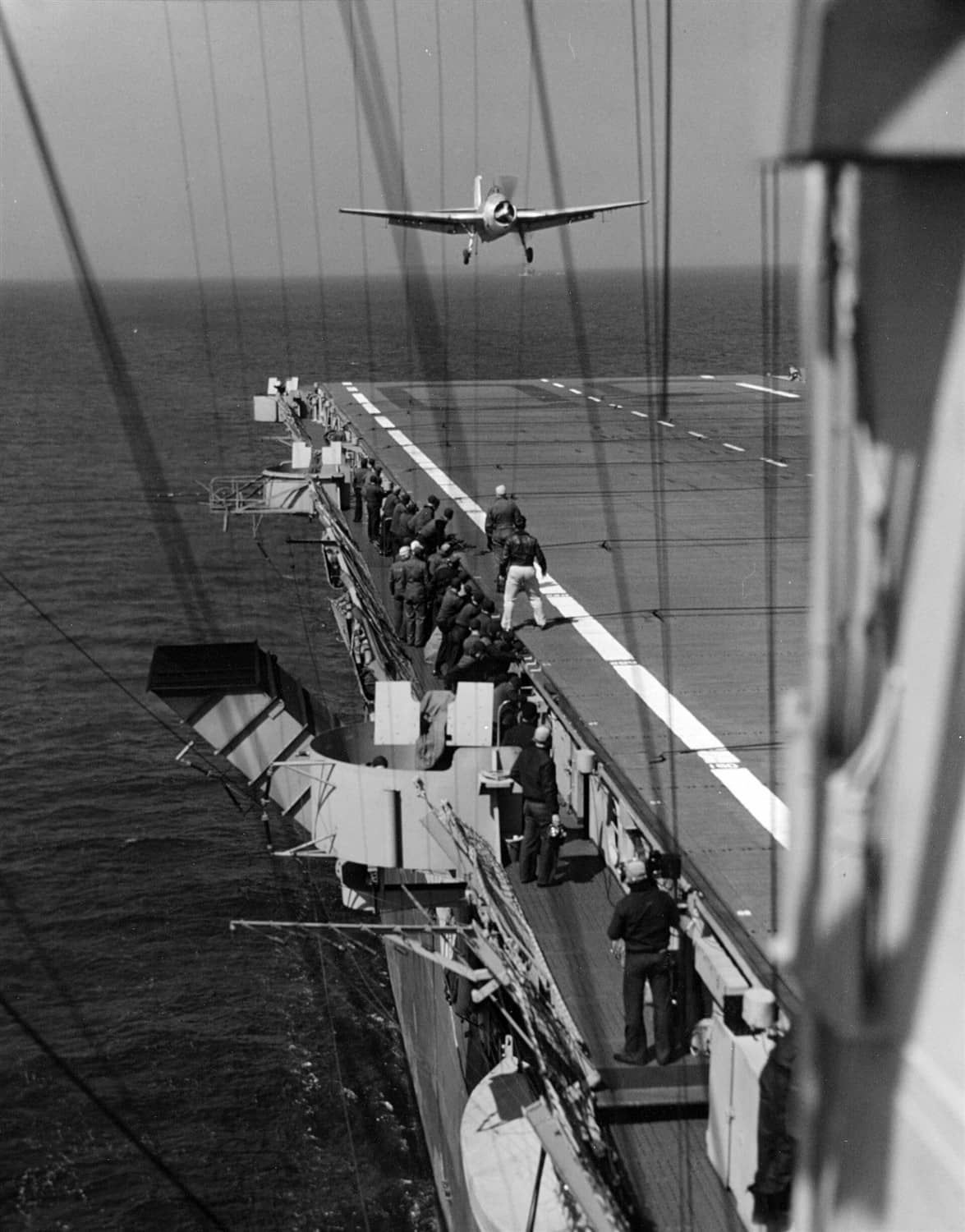 1944年4月22日,切萨皮克湾,一架 TBF/TBM「复仇者」鱼雷机正在「充电者」号(CVE-30)上降落。照片可见甲板两侧的飞行甲板人员与该舰特有的棱角状烟囱。