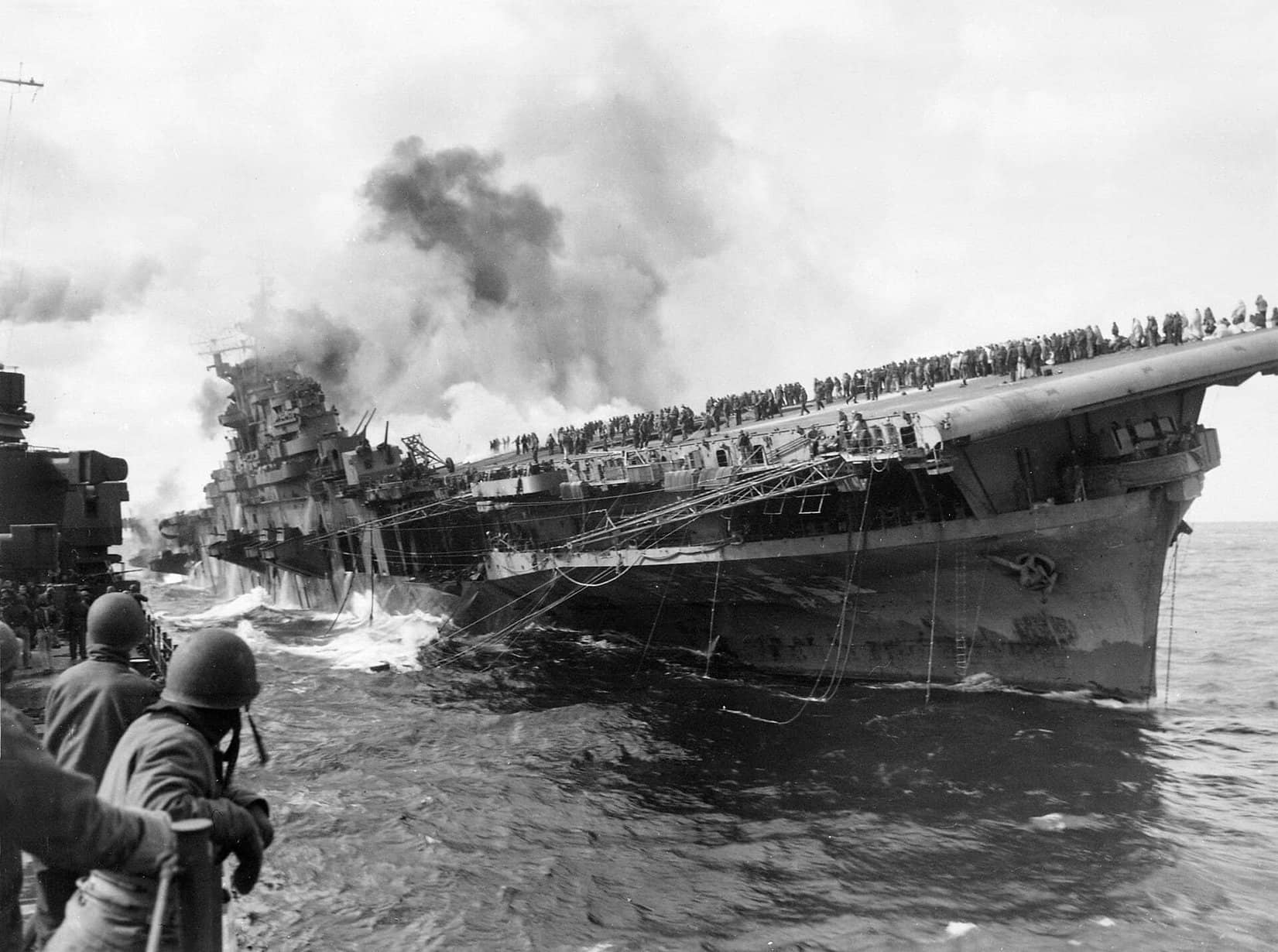 1945年3月19日,日本近海,富兰克林号航空母舰(CV-13)被炸弹命中后起火倾斜,巡洋舰「圣菲」号靠帮协助灭火与救援。