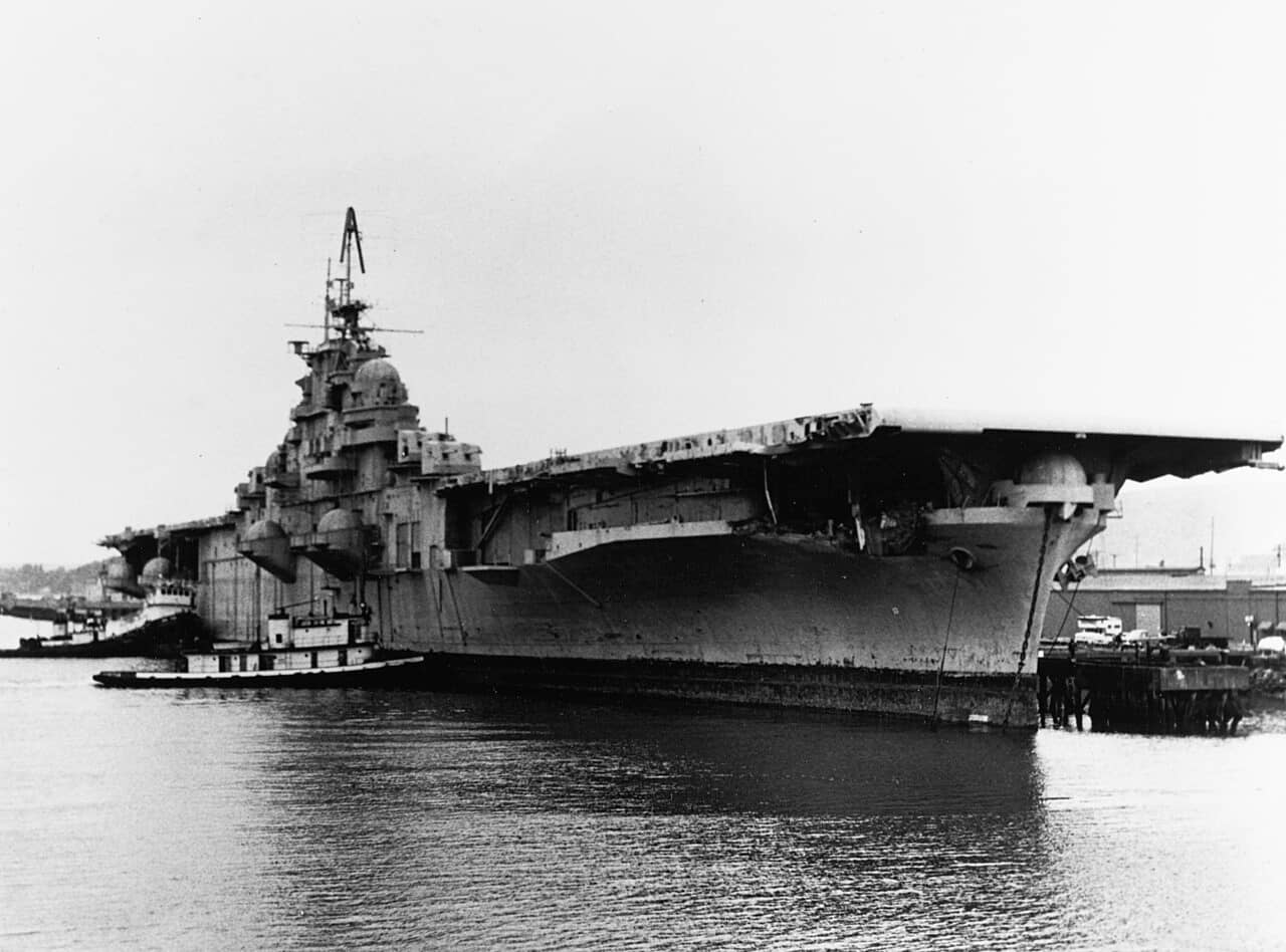 1973年4月,美国海军邦克山号航空母舰(CV-17)抵达美国华盛顿州塔科马,准备进行拆解。在拖带航行途中,邦克山号曾遭一艘希腊油轮撞击受损,这便是其舰艏区域受损的原因。注意,舰艏处仍标有较小的舷号「17」。