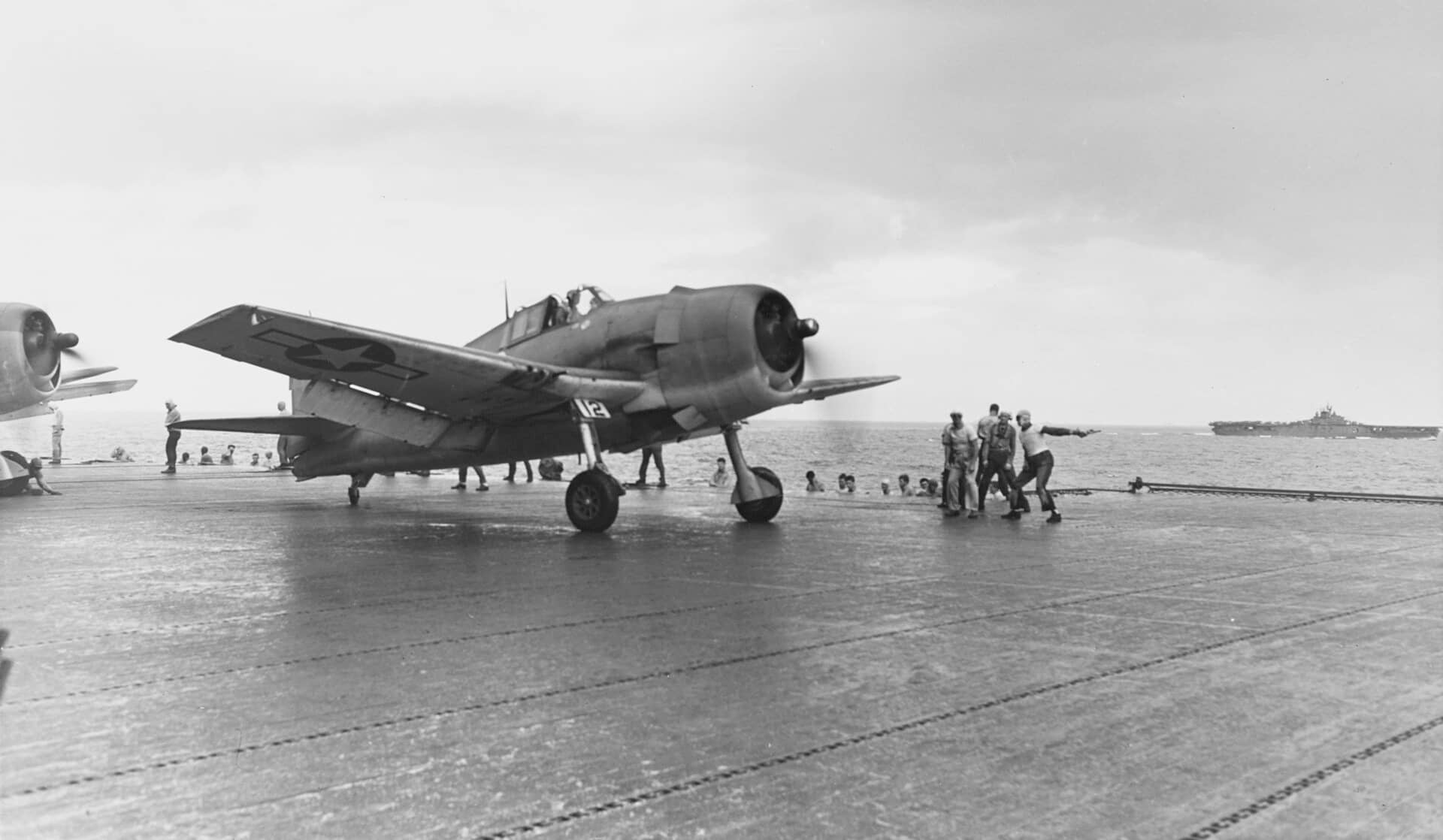 1944年2月,特鲁克环礁,「冰雹行动」首日,第9战斗机中队的 F6F-3「地狱猫」从埃塞克斯号航空母舰(CV-9)起飞;背景中为另一艘埃塞克斯级航母「勇猛」号(CV-11)。