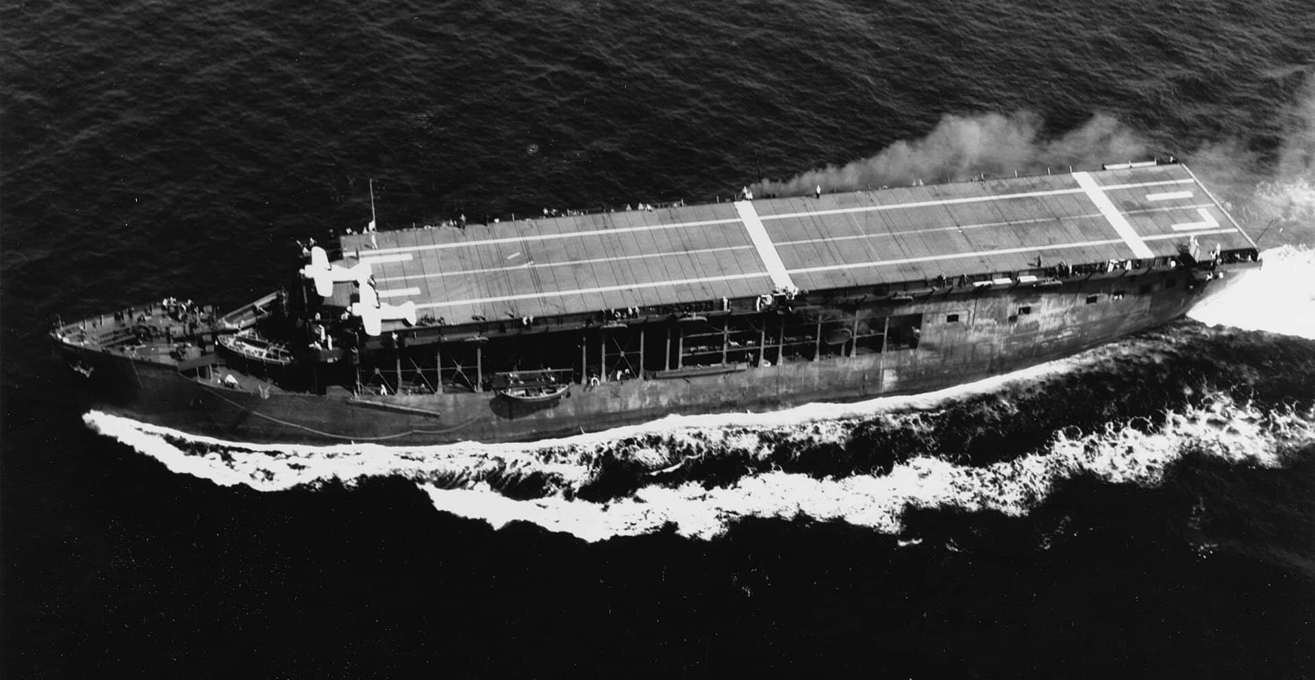 1941年7月8日,正在航行中的美国海军长岛号护航航空母舰(AVG-1),其飞行甲板前端停放着两架布鲁斯特 F2A 战斗机。注意飞行甲板上的「LI」标识。该舰采用了「第1号伪装方案」(Camouflage Measure 1),舰体侧面的漆面呈现出明显的严重风化磨损痕迹。